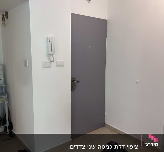 דלת אפורה עם ידית מתכת על קיר לבן